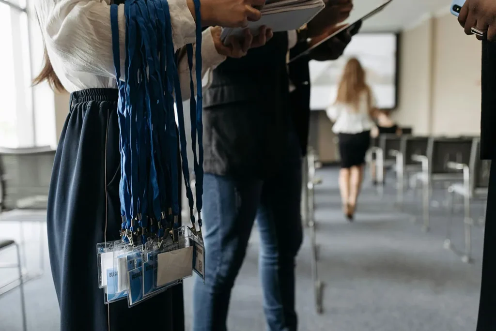 A person holding a large bunch of blue lanyards with name tags attached, possibly for an event or conference.