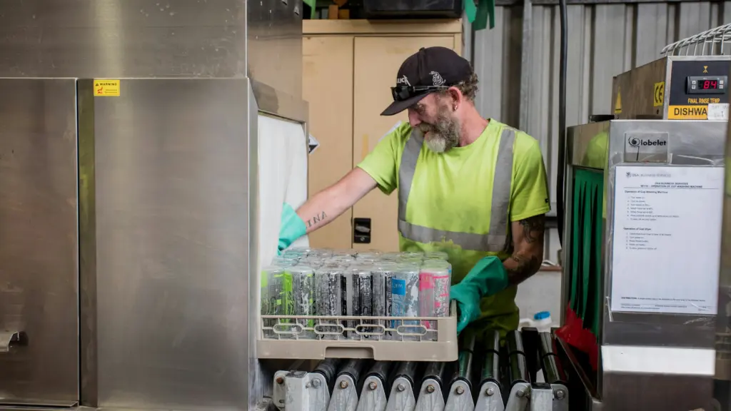 A worker processes reusable bottles as part of a reuse and refill system