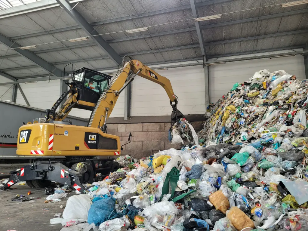 A backhoe loader inside a waste storage warehouse 