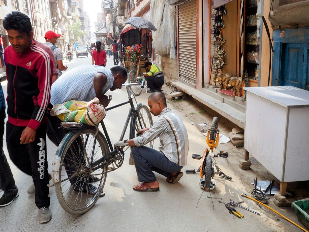two men repairing a bike in the street