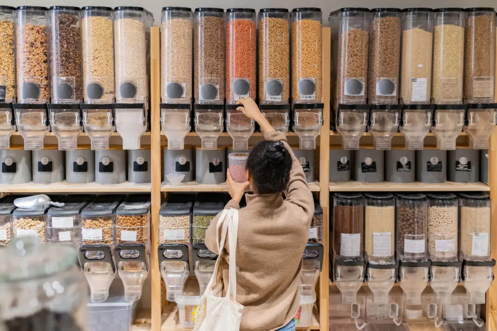 A woman refilling reusable package with products in a local grocery store