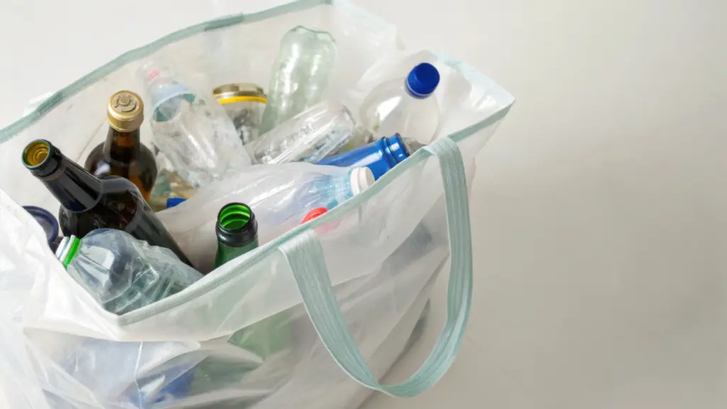 A reusable bag filled with empty glass and plastic bottles ready for recycling